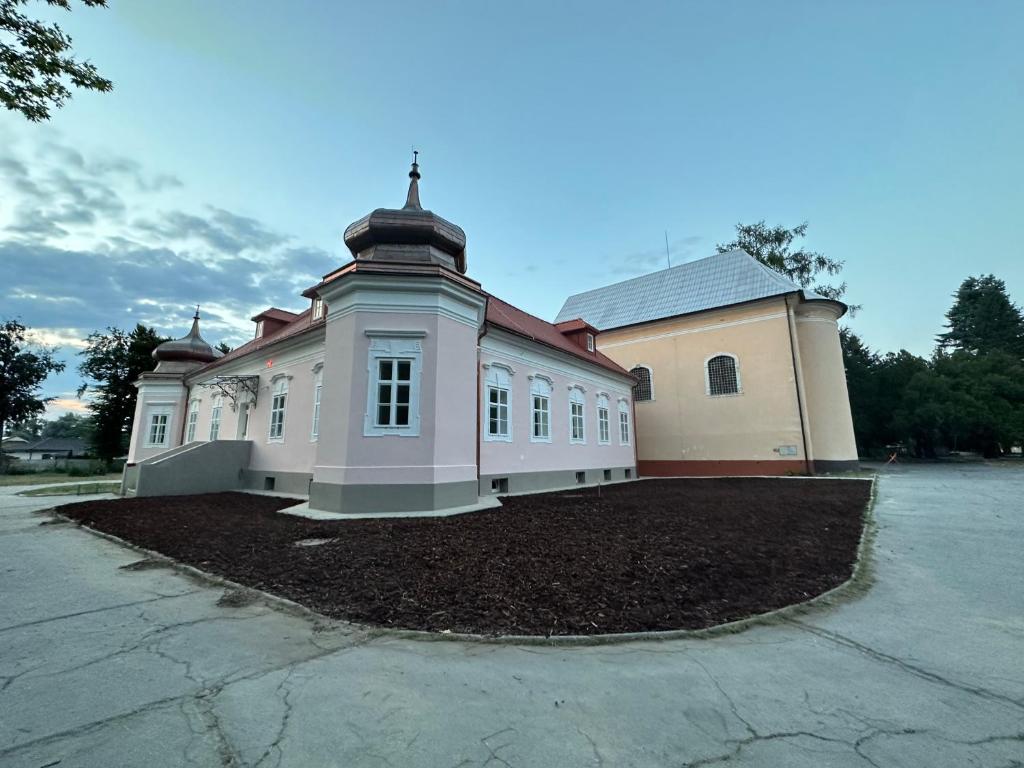 um grande edifício branco com uma cruz em cima em Kaštieľ Ladce 