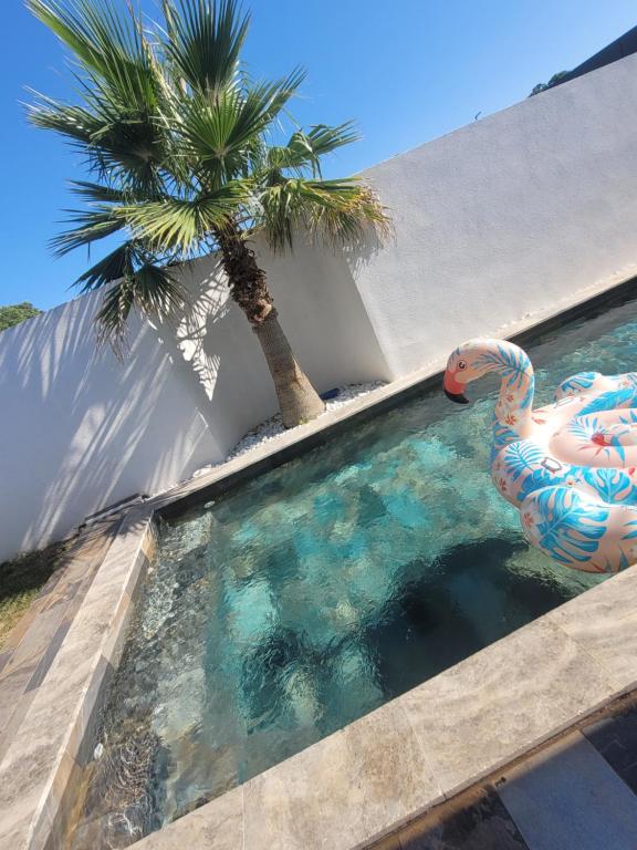 a swimming pool with a statue of a swan and a palm tree at LaVillaEden13 in Gignac-la-Nerthe