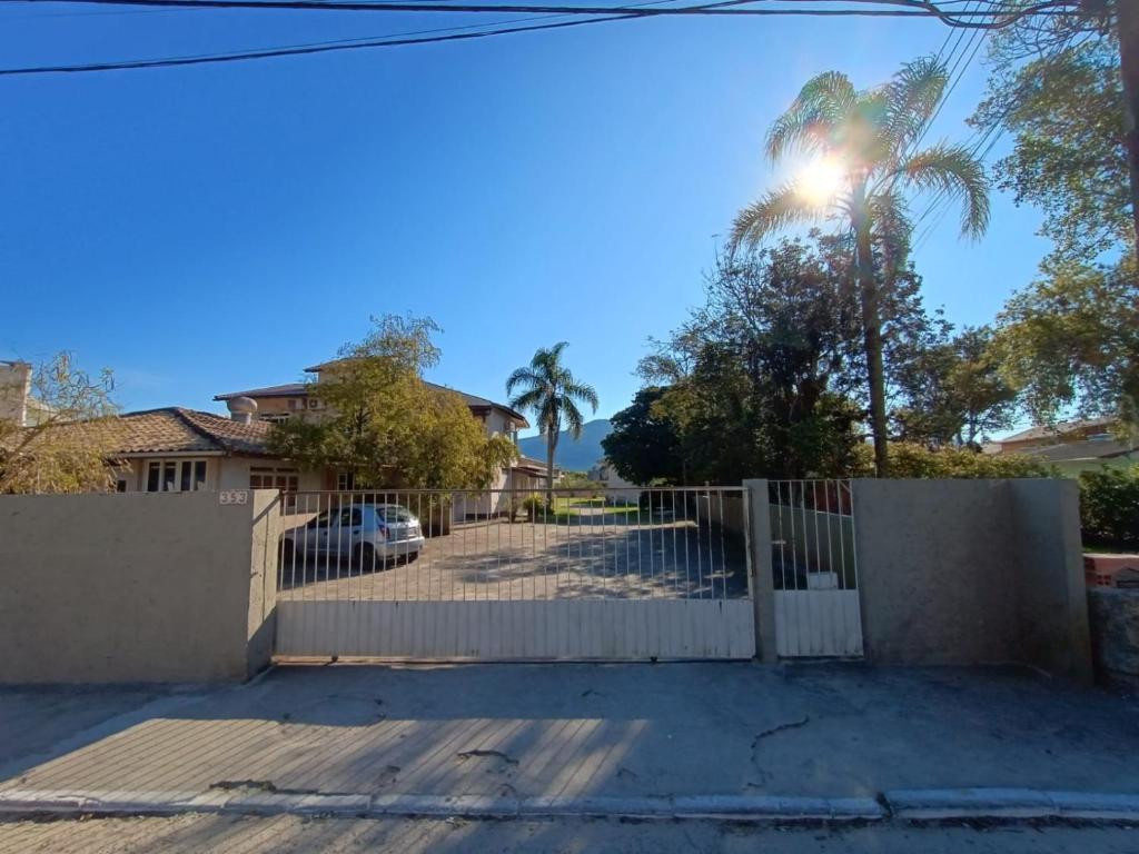 une maison avec une clôture blanche et un palmier dans l'établissement Residencial Caramujo, à Florianópolis