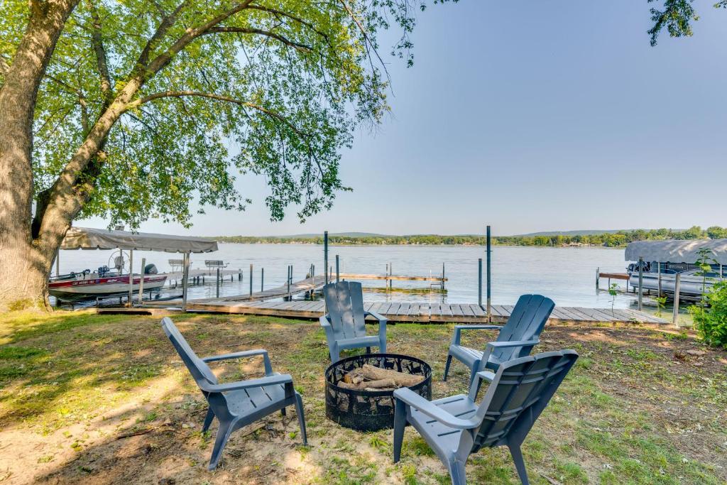 a group of chairs and a fire pit next to the water at Waterfront Lodi Vacation Rental on Lake Wisconsin! in Lodi