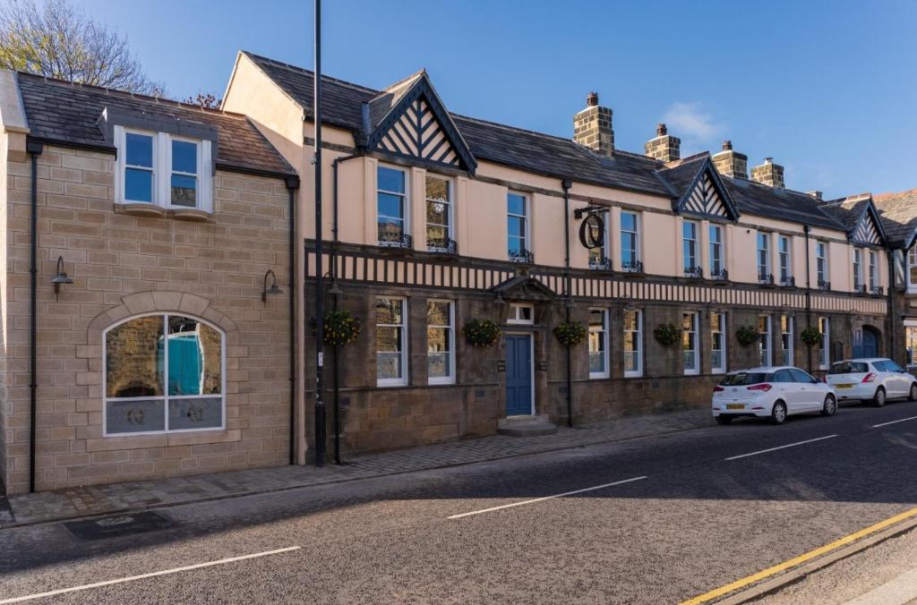 un edificio en una calle con coches aparcados delante en The Queens Head, Parkside apartment 2, en Burley in Wharfedale