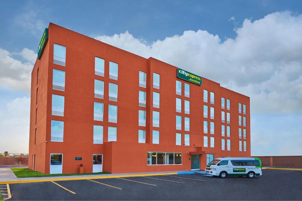 a red building with a van parked in a parking lot at City Express Junior by Marriott Mexicali in Mexicali