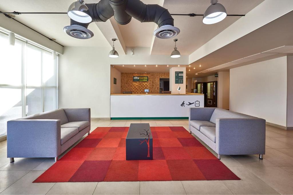 vestíbulo con 2 sofás y mesa de centro en City Express Junior by Marriott Toluca Zona Industrial, en Toluca