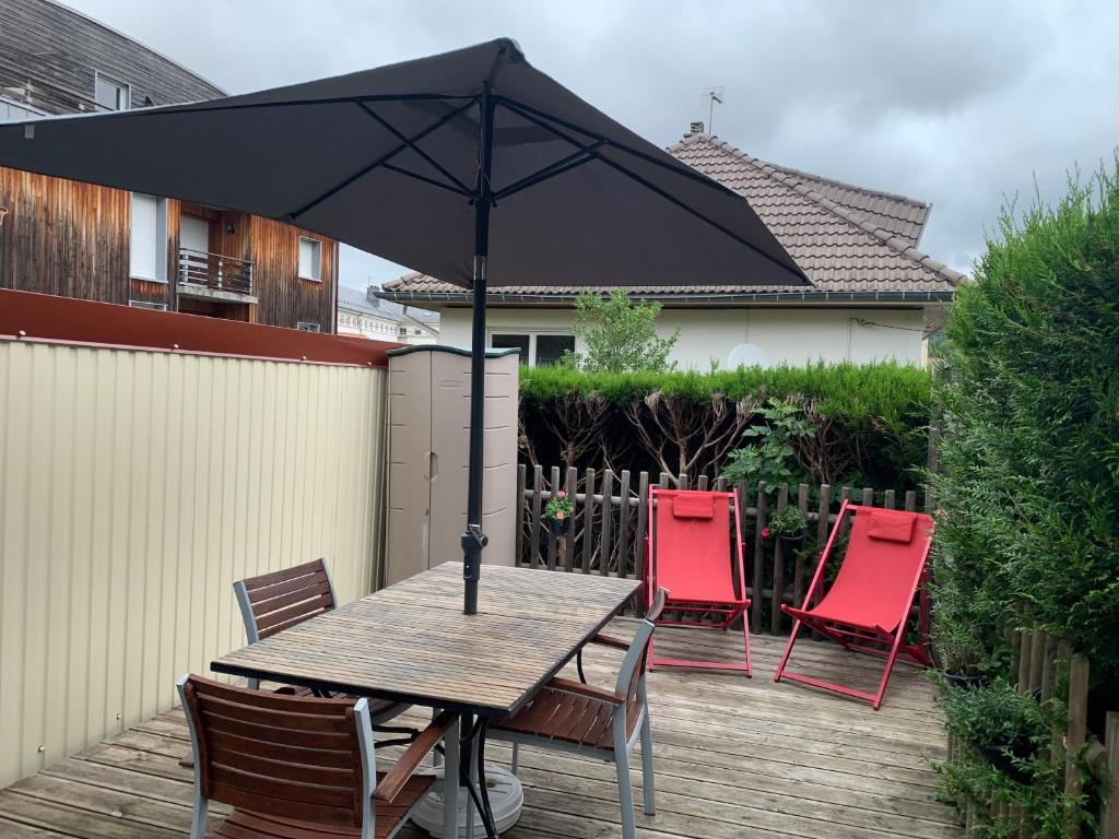 a table and chairs with an umbrella on a deck at Chalet Élise Plein centre ville in Gérardmer