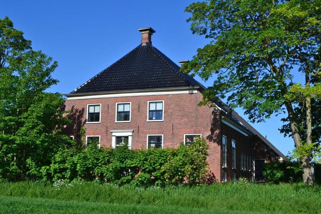 un gran edificio de ladrillo con techo negro en Apartment Noorderloft, en Hornhuizen