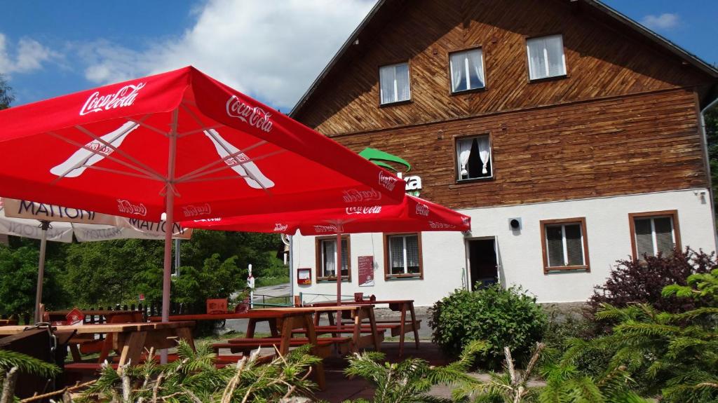 a cocacola umbrella and tables in front of a building at Hotel Alfonska in Benecko