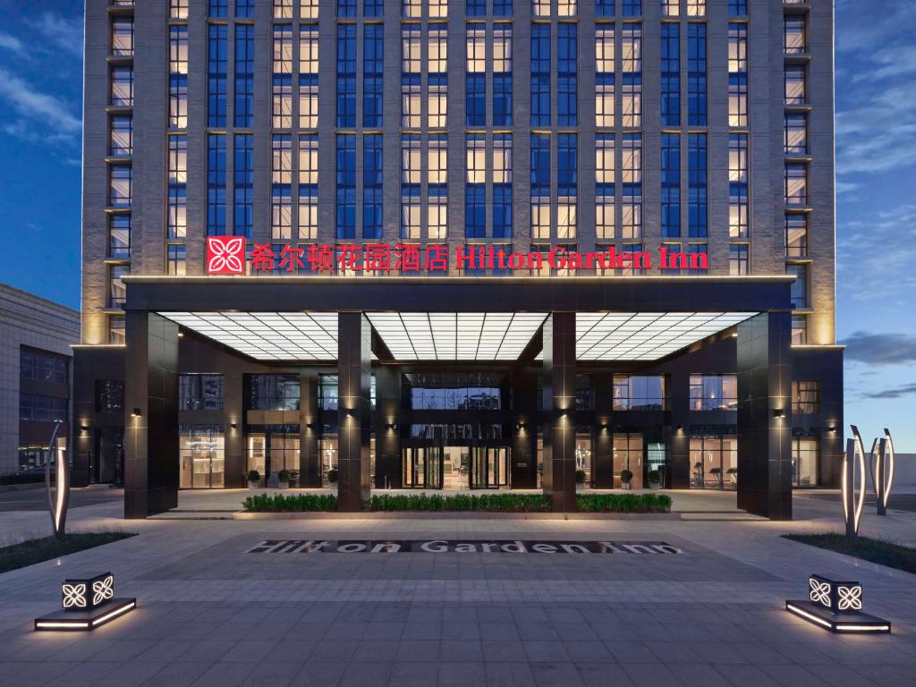 een groot gebouw met een bord ervoor bij Hilton Garden Inn Tianjin Huayuan in Tianjin