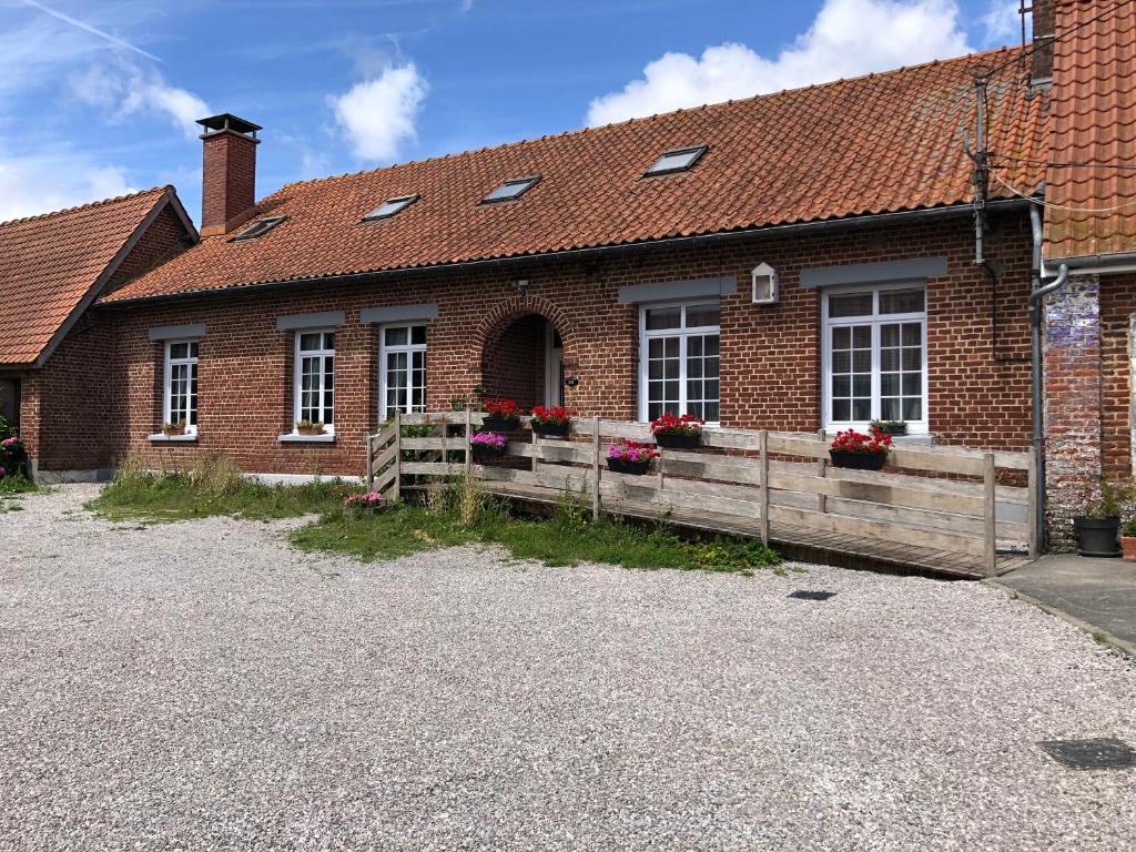 une maison en briques avec une clôture en bois et des fleurs dans l'établissement Entre Caps et Marais la FERME, à Alembon