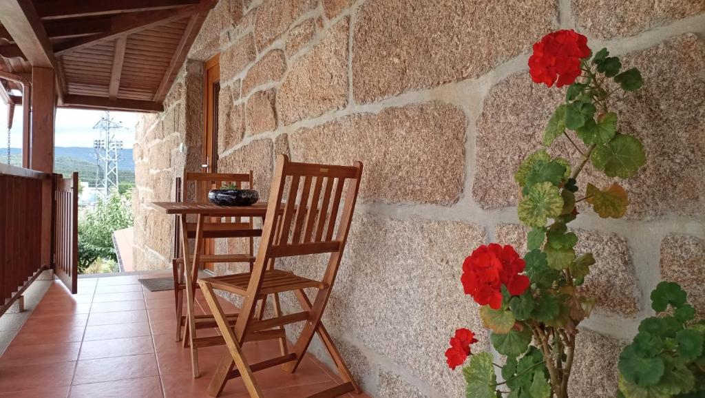 Habitación con 2 sillas, mesa y pared de piedra. en Antiga Casa do Forno, en Vidago