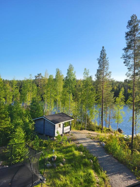 uma pequena cabana na floresta ao lado de um lago em Viherpeukalo lomamökki em Parkano