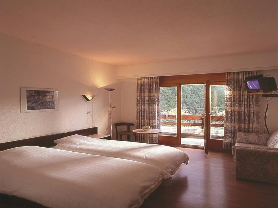 Hotel du Pigne في أرولّا: غرفه فندقيه بسرير وشرفه