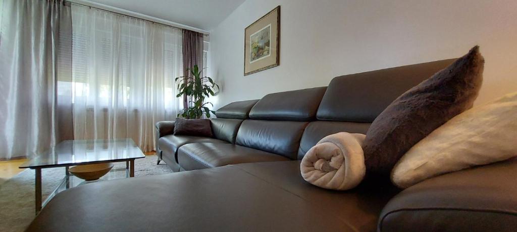 a living room with a brown leather couch with pillows at 3 min. away in Koprivnica