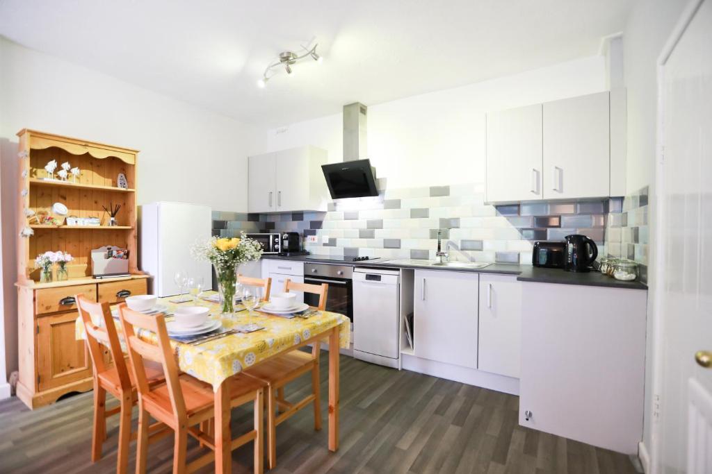 a kitchen with a table and chairs and a kitchen with white cabinets at Woodside Ash hot tub & pool (sleeps 4-6) in Bideford