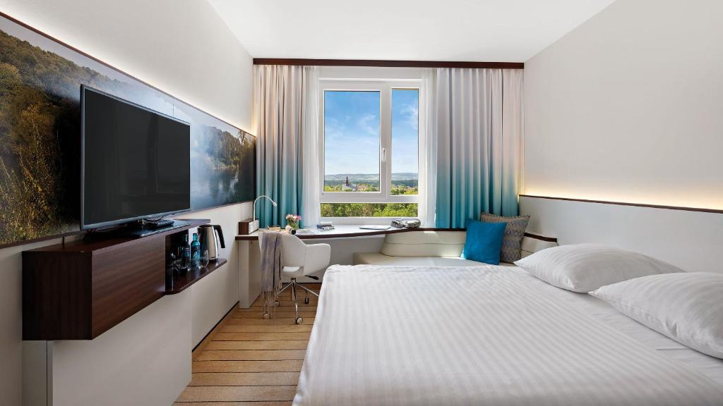 Dormitorio con cama, escritorio y TV en Hey Lou Hotel Frankfurt Airport, en Kelsterbach