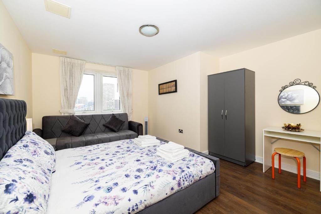 a bedroom with a bed and a couch and a desk at Two bed Apartment near Canary Wharf in London