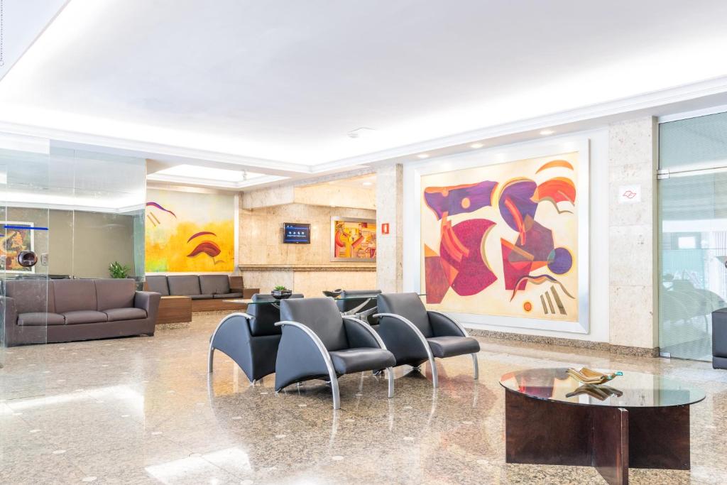 a lobby with chairs and a large painting on the wall at Braston Augusta Hotel by Castelo Itaipava in São Paulo