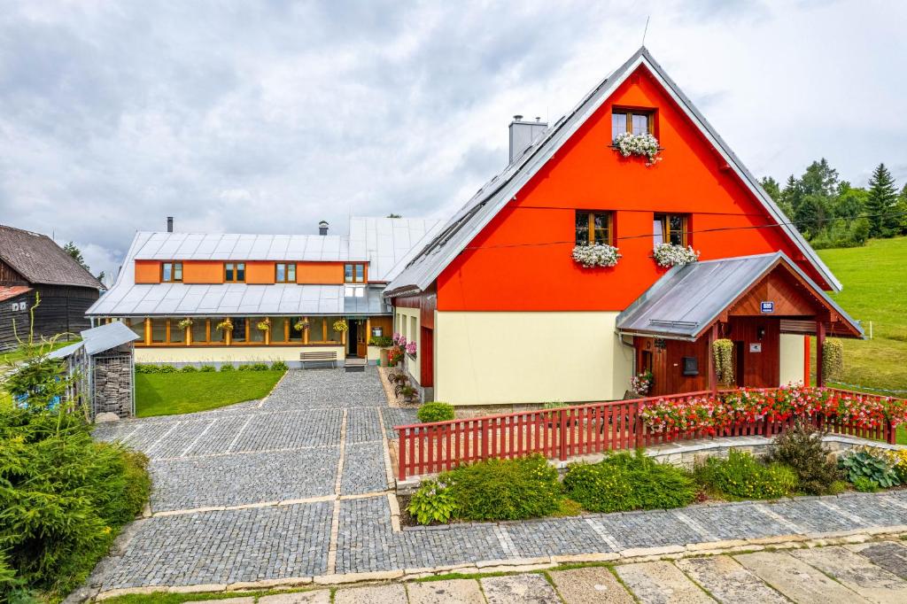 ein orangefarbenes und weißes Haus mit Auffahrt in der Unterkunft Penzion Podkůvka in Kořenov