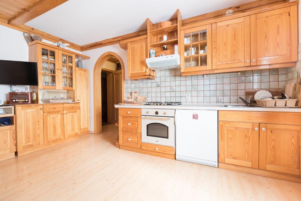 una cucina con armadietti in legno ed elettrodomestici bianchi di Apartmajska hiša Muštrinka a Cerklje na Gorenjskem