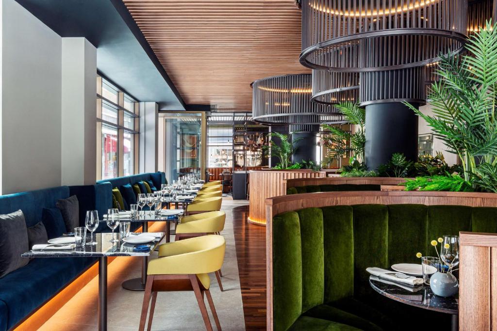 a dining room with tables and chairs and plants at Radisson Collection Hotel, Magdalena Plaza Sevilla in Seville