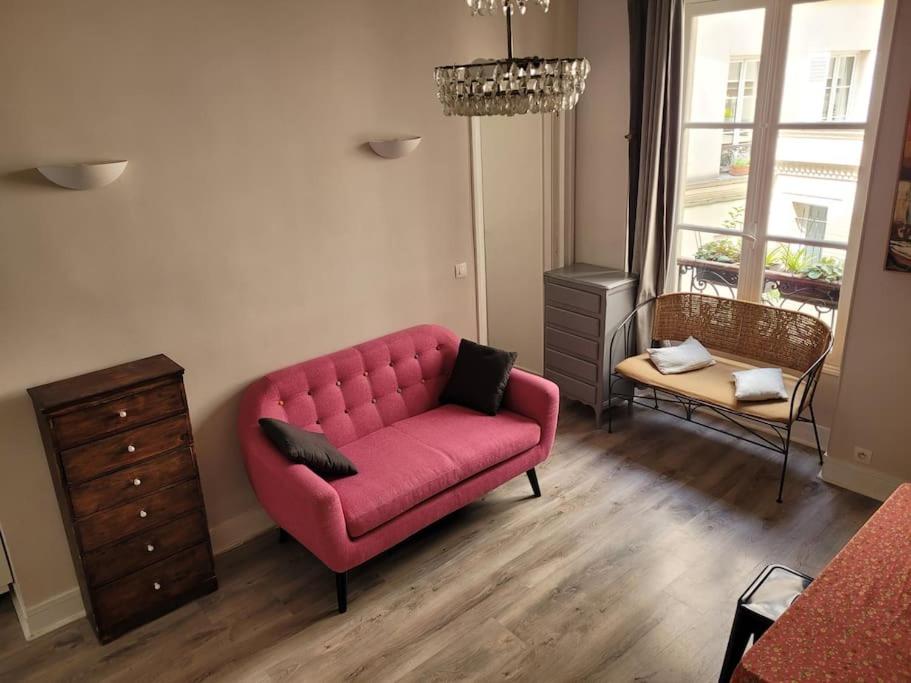 uma sala de estar com um sofá rosa e uma cómoda em Appartement entier - Paris 12 em Paris
