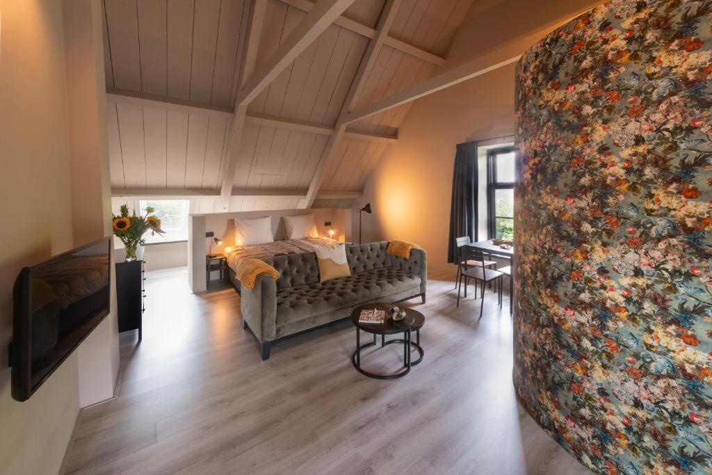 a living room with a couch and a bed in a room at Landelijke boerderijkamer, dichtbij Kinderdijk in Oud-Alblas