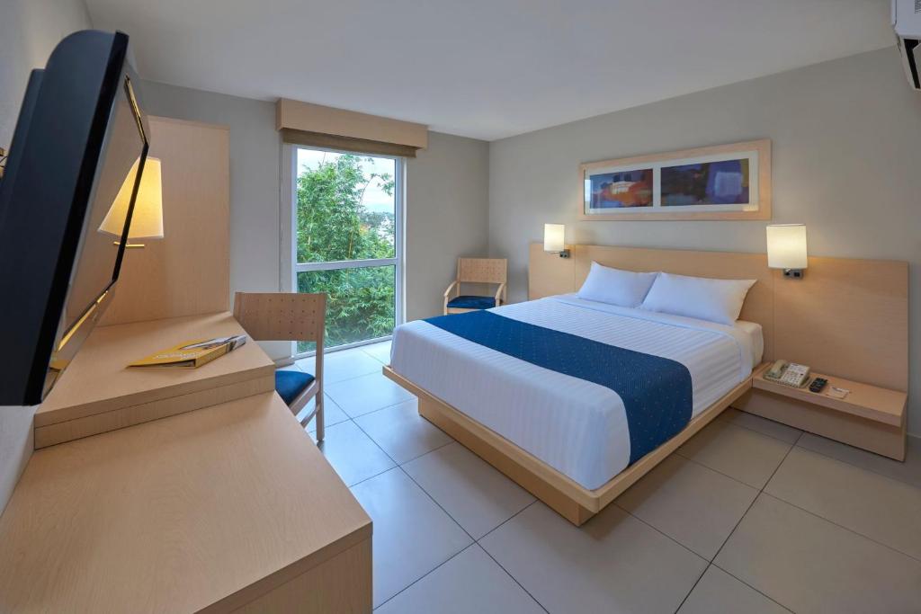a bedroom with a bed and a desk with a television at City Express by Marriott Xalapa in Xalapa