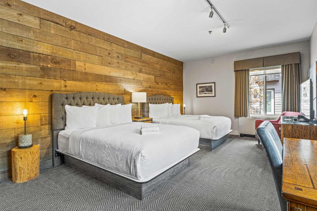 a bedroom with two beds and a wooden wall at Basecamp Lodge Canmore in Canmore