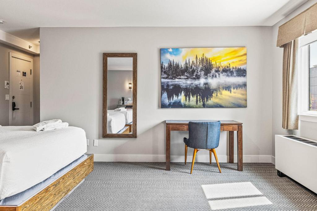 a bedroom with a bed and a desk and a mirror at Basecamp Lodge Canmore in Canmore