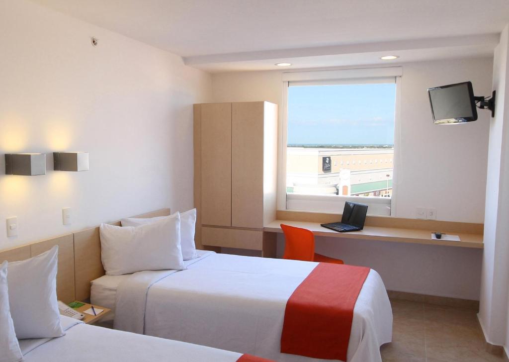 a hotel room with two beds and a window at One Coatzacoalcos Forum in Coatzacoalcos