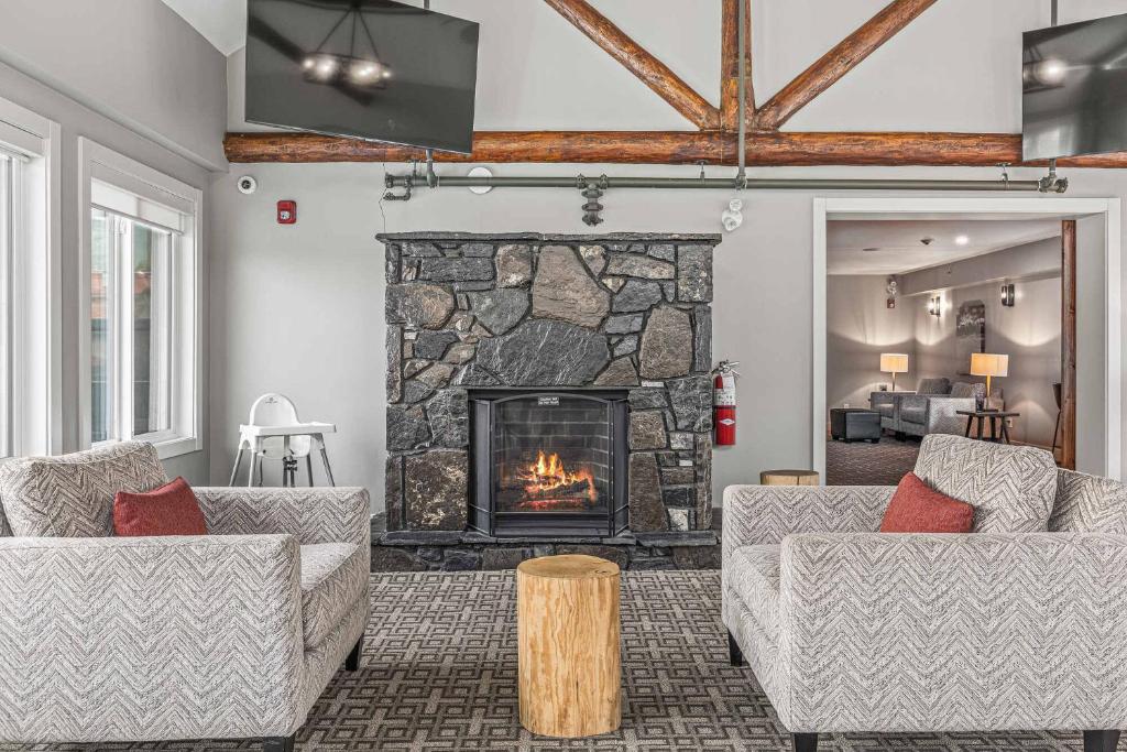 a living room with two couches and a stone fireplace at Basecamp Lodge Canmore in Canmore