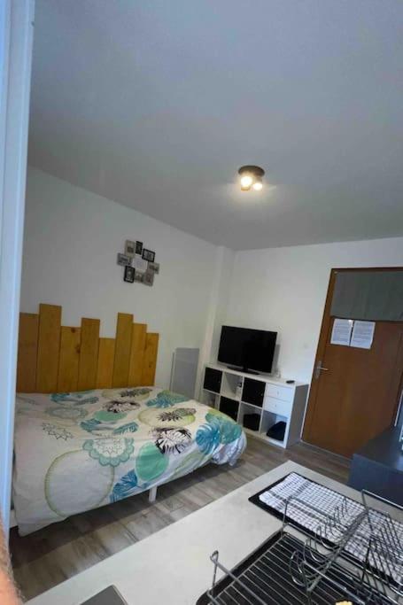 Schlafzimmer mit einem Bett und einem Schreibtisch mit einem TV in der Unterkunft Logement 2 personnes. in Vitry-le-François