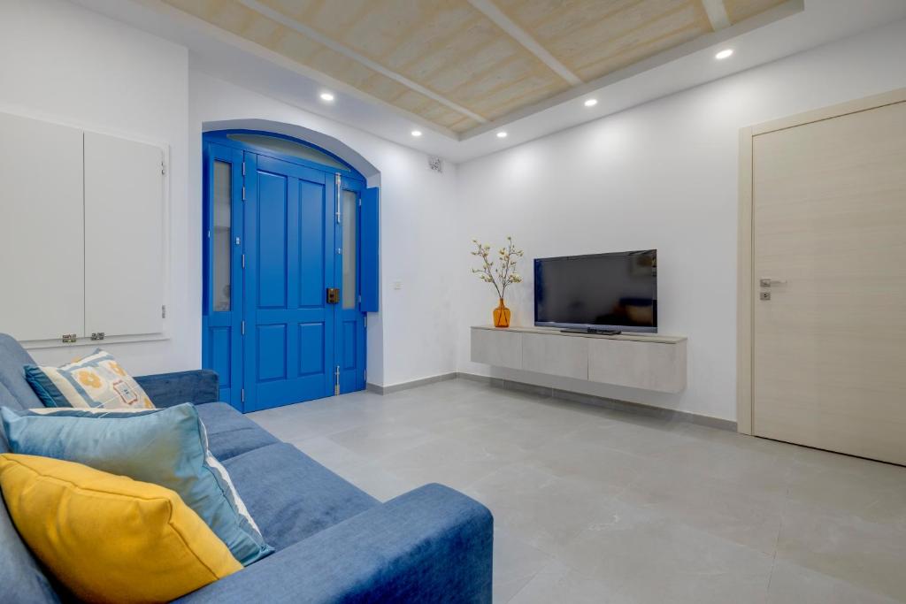 a living room with a blue couch and a tv at Kapitali 33A in Valletta