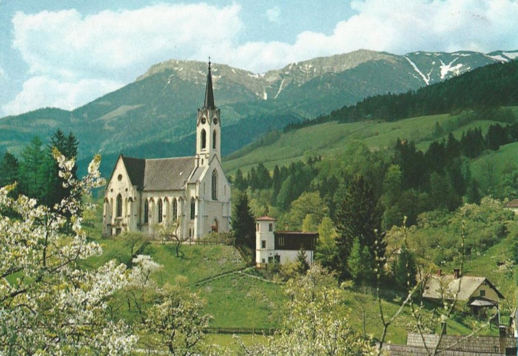 a church on a hill with mountains in the background at Gemütliche Ferienwohnung - Prein an der Rax 