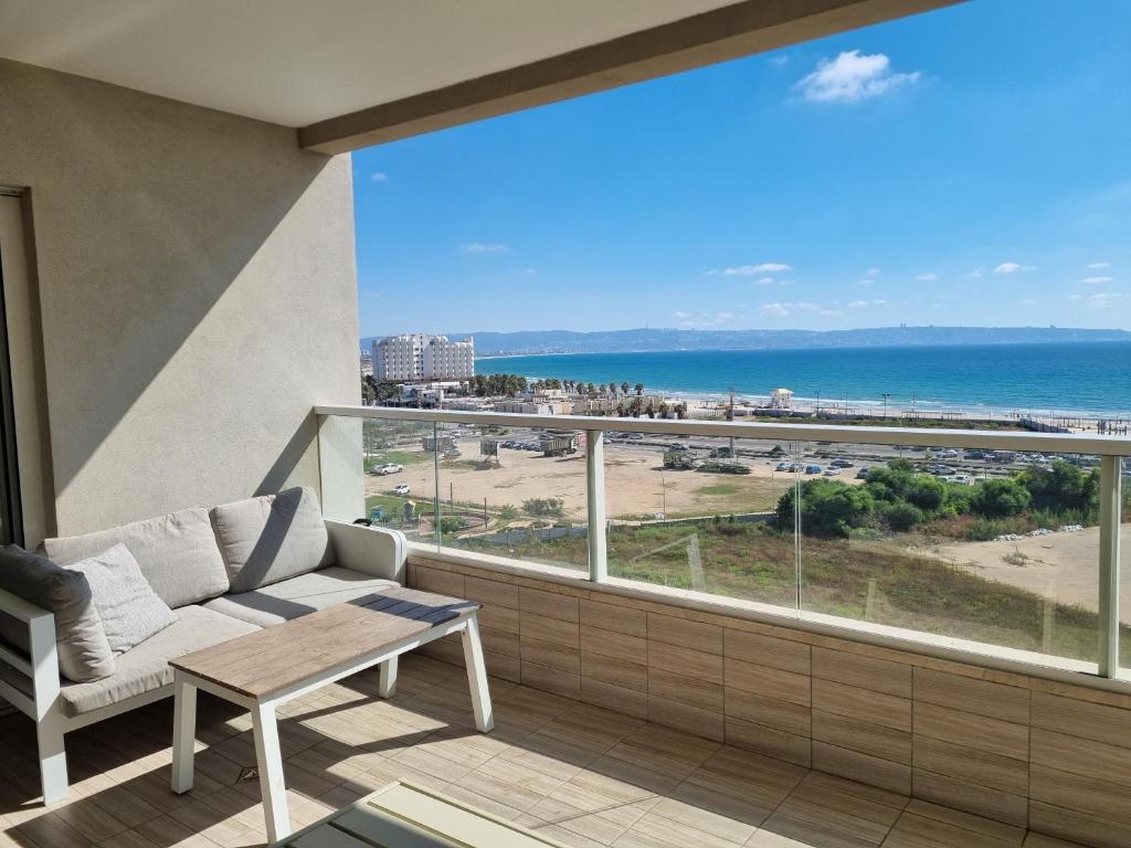 ein Balkon mit Sofa und Blick auf den Strand in der Unterkunft 7th Floor in Akkon