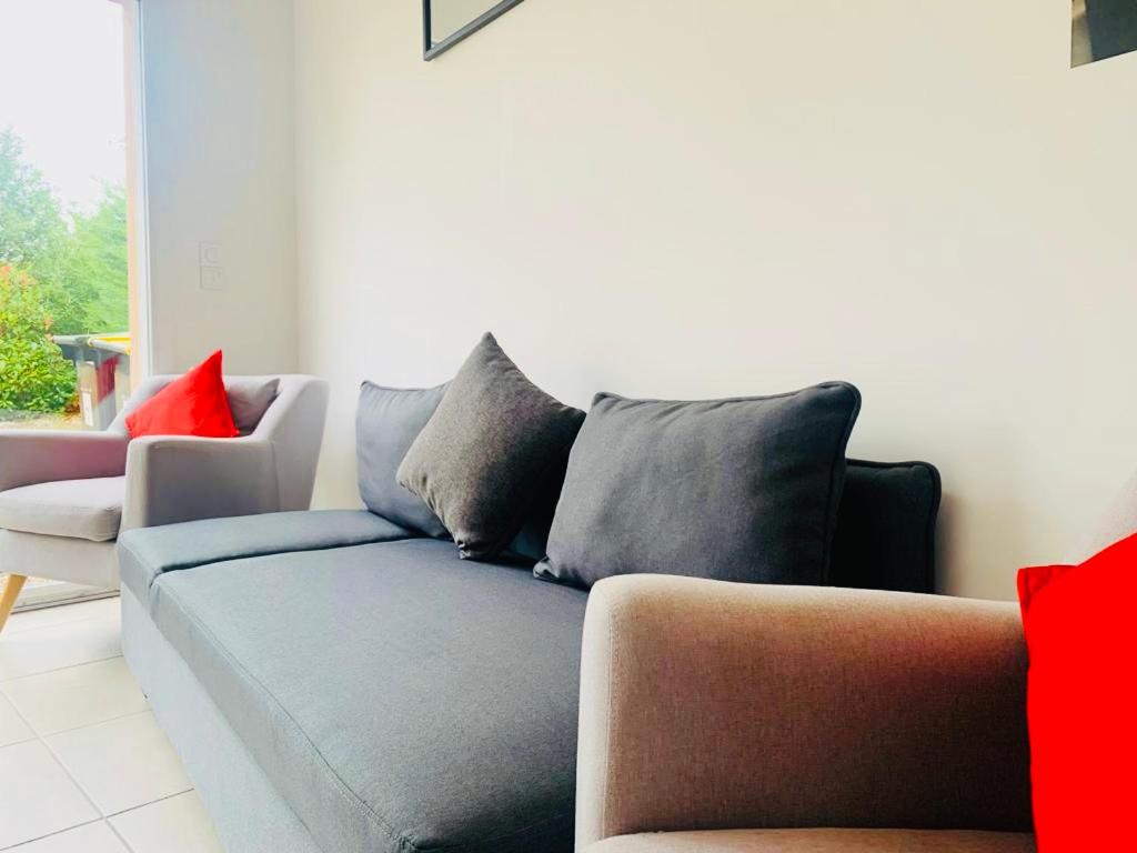 sala de estar con sofá azul y almohadas rojas en Maison plain-pied avec accès PMR, en Warcq