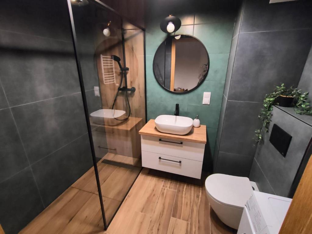 a bathroom with a toilet and a sink and a mirror at Apartament Leśna Mandala in Augustów