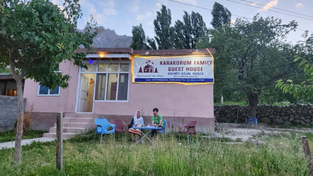 dwoje ludzi siedzących przy stole przed domem w obiekcie Karakorum Family Guest House Hunza w mieście Hunza