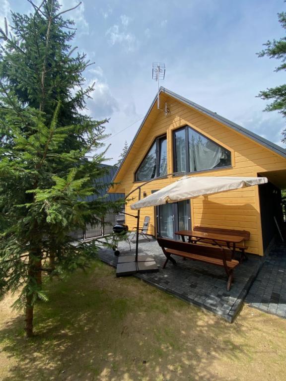 拉達瓦的住宿－Domki AS，黄色的房子,配有野餐桌和雨伞