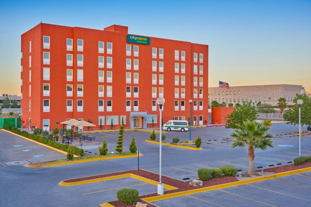 un edificio rojo con un estacionamiento delante de él en City Express Junior by Marriott Juarez Consulado en Ciudad Juárez