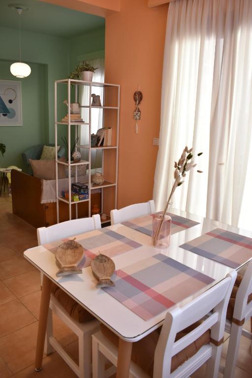 a dining room table with white chairs and a table at ΆLthea Apartment in Chalkida