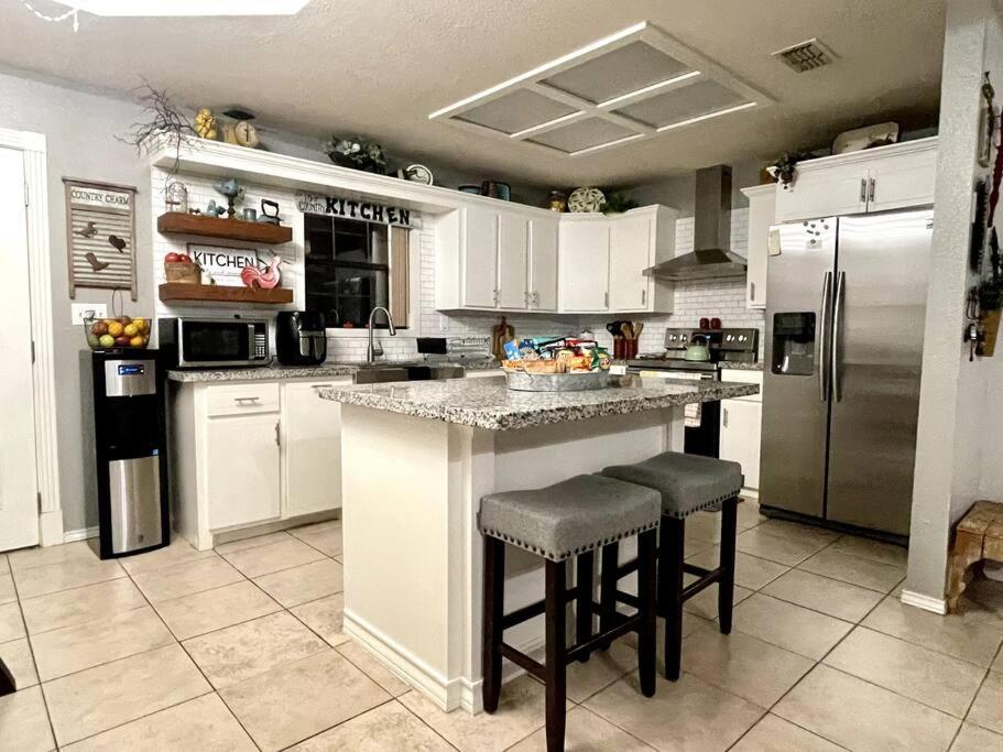 una cocina con armarios blancos y una isla con taburetes. en Rest, Relax & enjoy the entire cozy vacational home!, en Mission