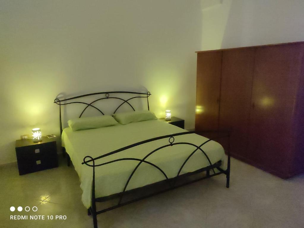 een slaapkamer met een bed en een houten kast bij Casa Rosina in Castrignano del Capo