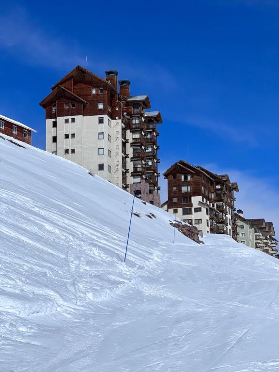 a snowy hill with buildings in the background at Ski-in/out. Amplio y cómodo Departamento in Lo Barnechea