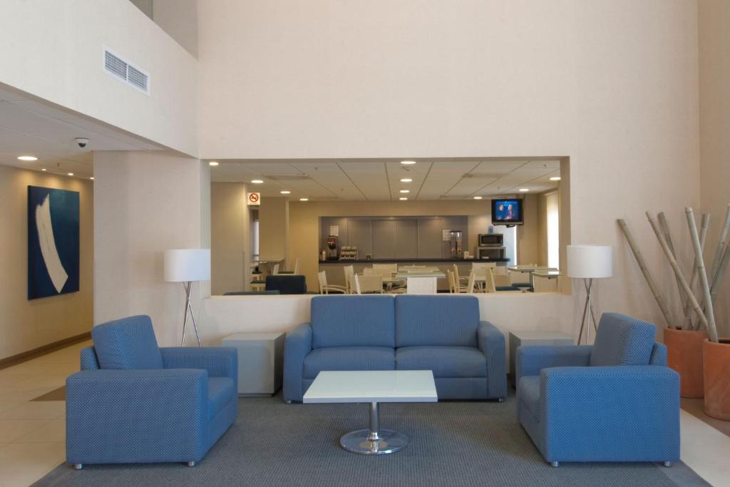 a waiting room with blue chairs and a table at City Express by Marriott Puebla Angelopolis in Puebla