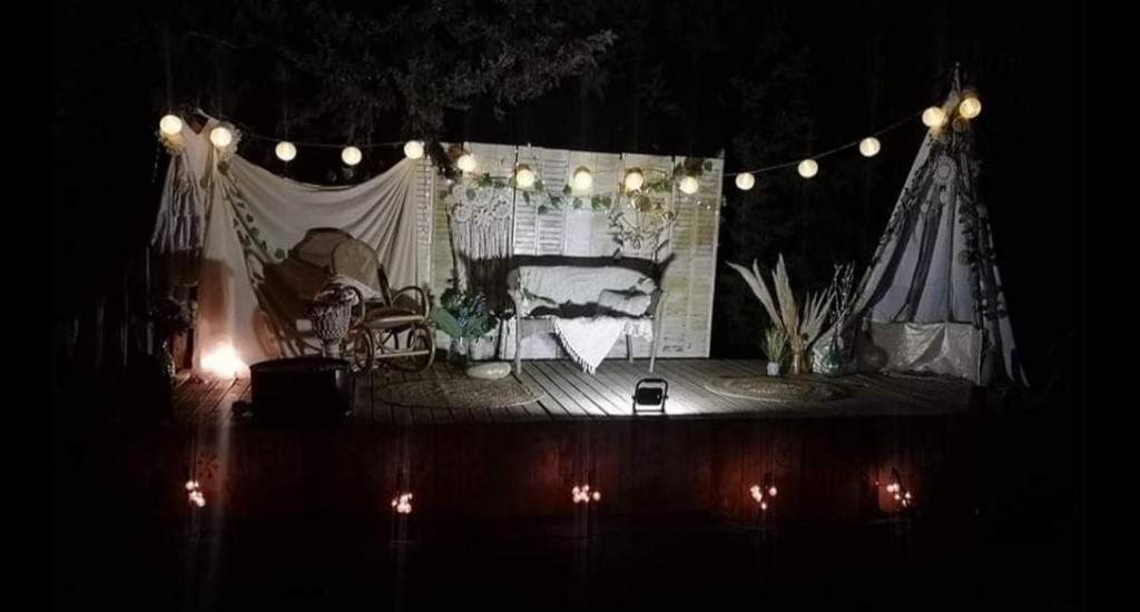 um palco com uma tenda e luzes à noite em Mobilhomes vintage dans ecolieux en cours camping a la ferme em Ponteilla