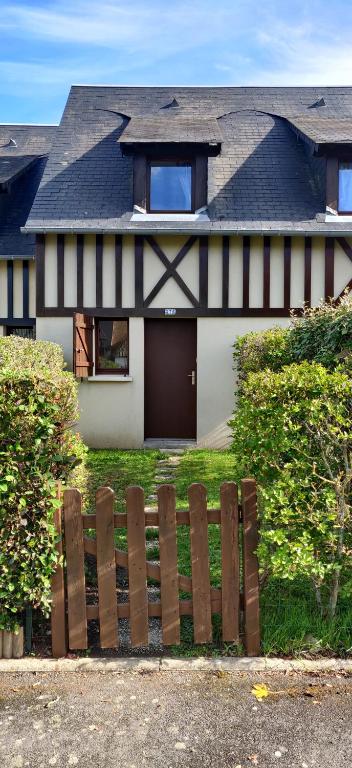 une maison avec une clôture en bois devant elle dans l'établissement Cottage Cabourg plage avec jardin et vélos, à Cabourg