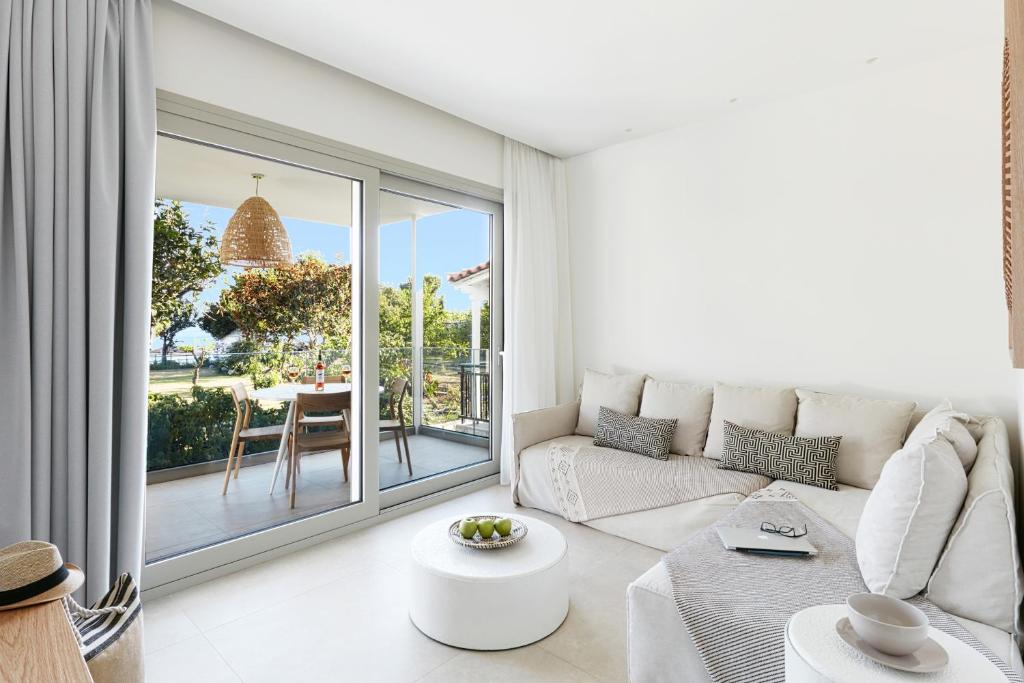 a white living room with a couch and a table at Skiathos Ammos Luxury Apartments in Skiathos