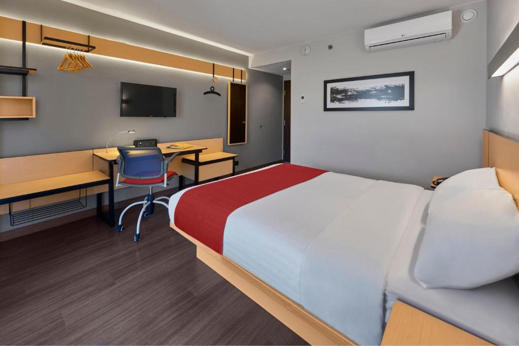 a hotel room with a bed and a desk and a computer at City Express by Marriott Tepic in Tepic