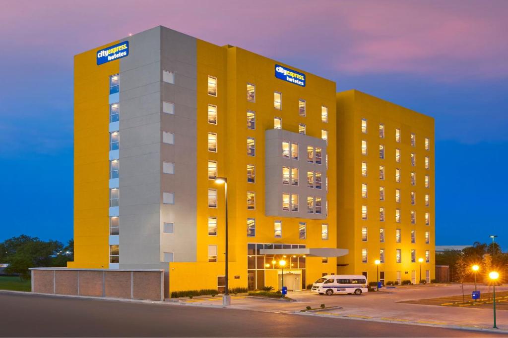 a yellow building with a van parked in front of it at City Express by Marriott Monterrey Lindavista in Monterrey