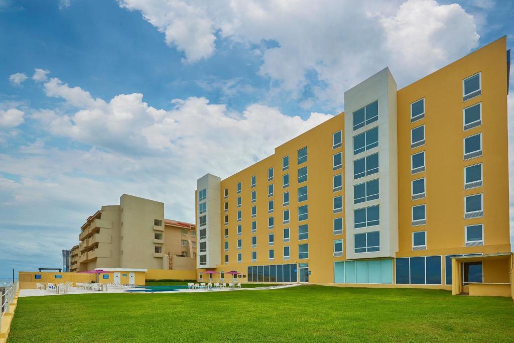 un grand bâtiment jaune avec une pelouse verte devant dans l'établissement City Express by Marriott Veracruz, à Veracruz